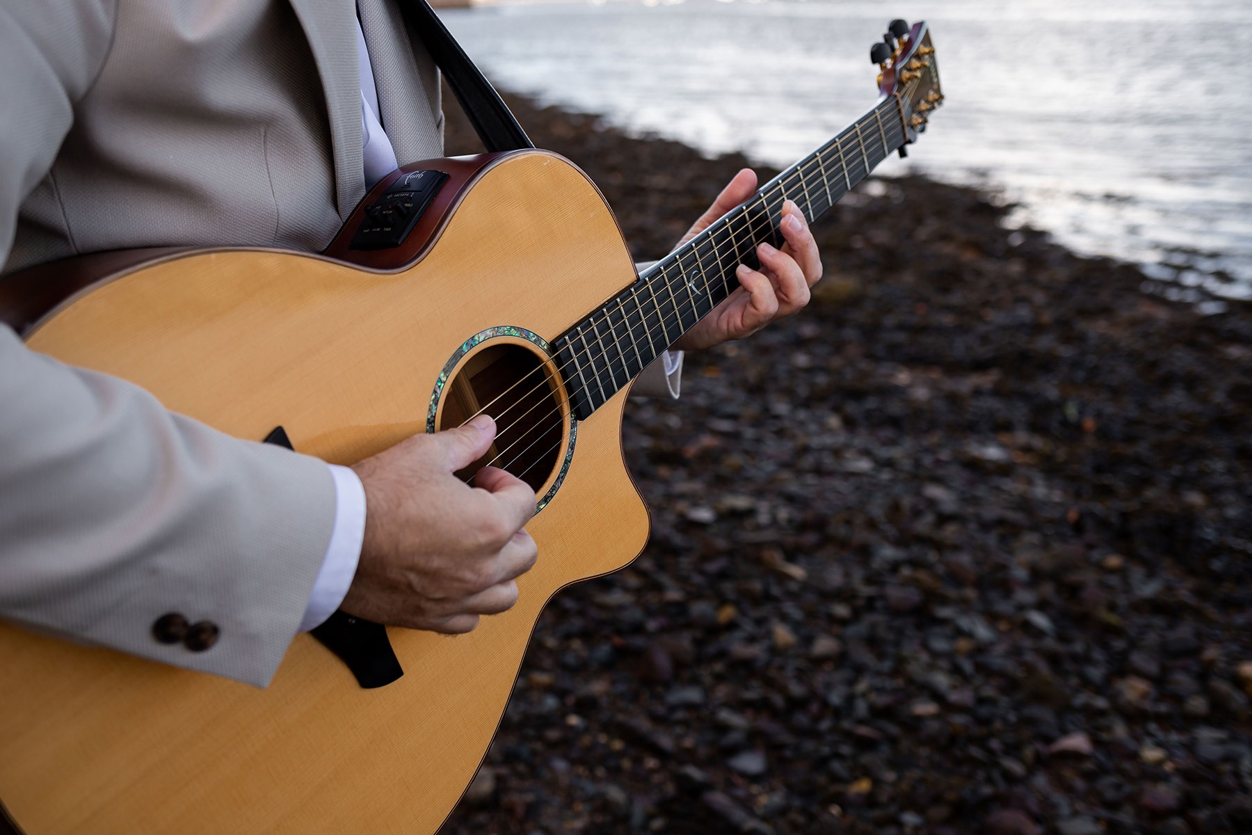 Devon wedding singer playing acoustic guitar by the sea – live music for coastal weddings in the South West UK